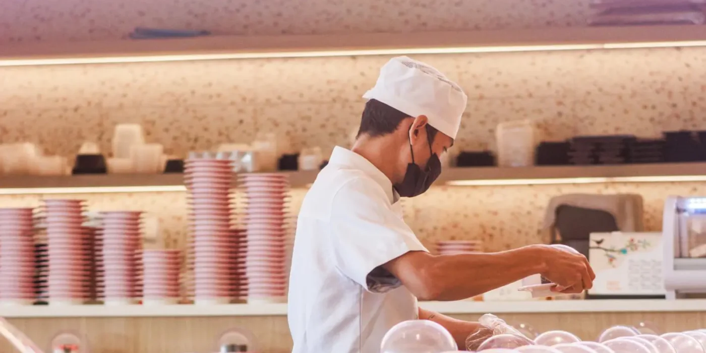 A Sushi Hiro chef placing fresh sushi plates on the kaiten belt