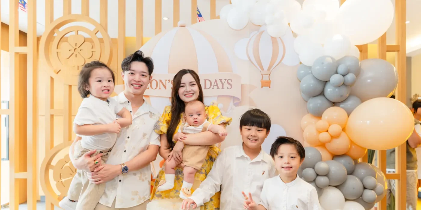 A family celebrating a baby’s 100 days in front of a balloon backdrop at Sushi Hiro